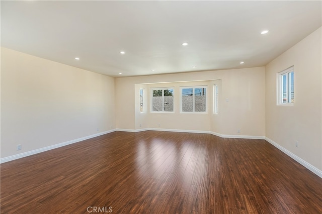 empty room with dark hardwood / wood-style floors and a wealth of natural light