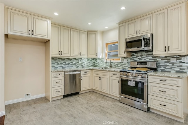 kitchen featuring tasteful backsplash, cream cabinets, stainless steel appliances, and sink