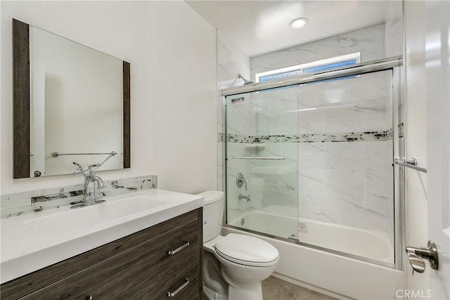 full bathroom featuring vanity, bath / shower combo with glass door, and toilet