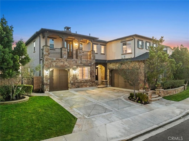 view of front of property featuring a garage, a balcony, and a yard