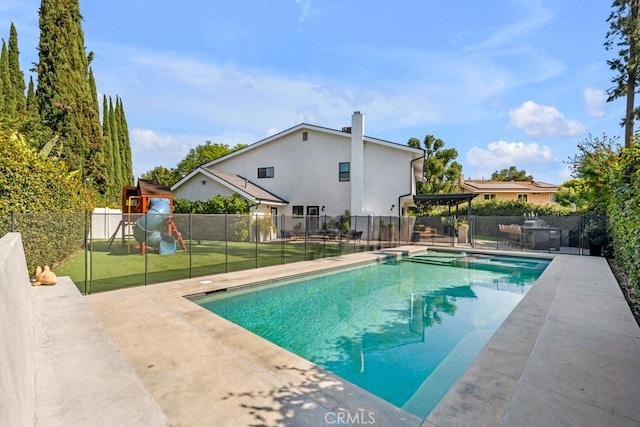 view of swimming pool with a lawn, a patio area, and a playground