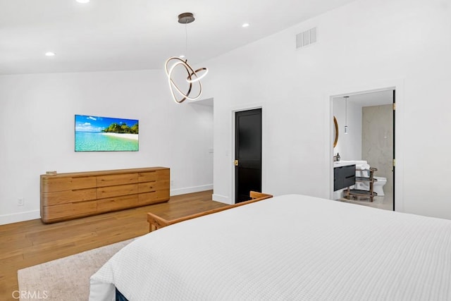 bedroom featuring wood-type flooring, ensuite bathroom, high vaulted ceiling, and a notable chandelier