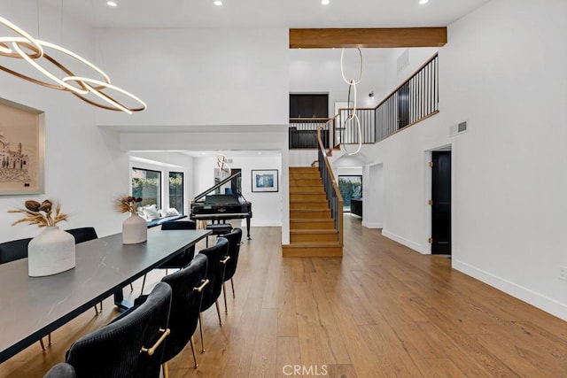 dining area with beam ceiling, hardwood / wood-style floors, and a high ceiling