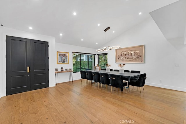 dining room featuring high vaulted ceiling and light hardwood / wood-style flooring