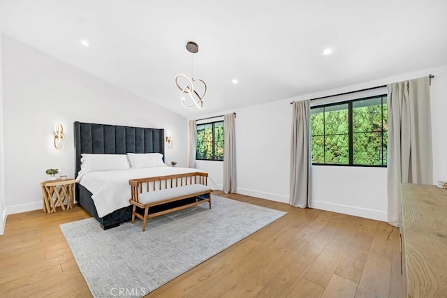 bedroom featuring light hardwood / wood-style floors, lofted ceiling, and a notable chandelier