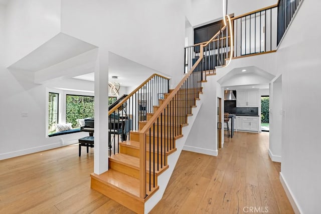 staircase with hardwood / wood-style flooring, a high ceiling, and a chandelier