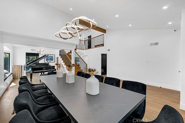 dining area with high vaulted ceiling, light hardwood / wood-style floors, and a notable chandelier