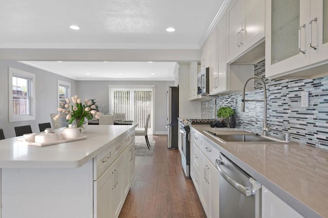 kitchen with sink, white cabinets, decorative backsplash, stainless steel appliances, and crown molding