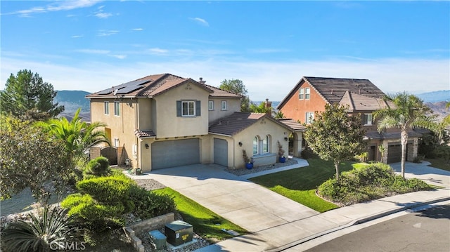 view of front of property featuring solar panels, a mountain view, a garage, and a front lawn