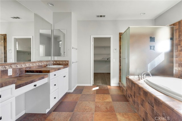 bathroom featuring vanity and independent shower and bath