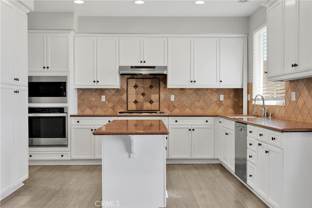 kitchen featuring a center island, appliances with stainless steel finishes, sink, and light wood-type flooring