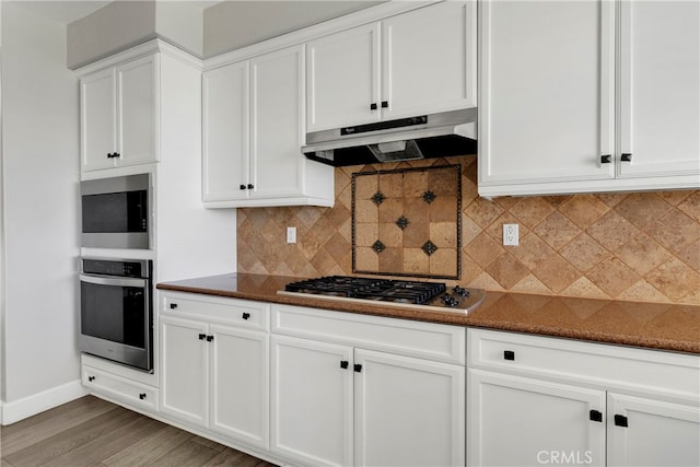 kitchen featuring white cabinetry, hardwood / wood-style flooring, appliances with stainless steel finishes, and decorative backsplash