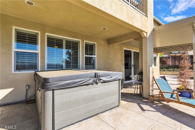 view of patio featuring a hot tub and a balcony