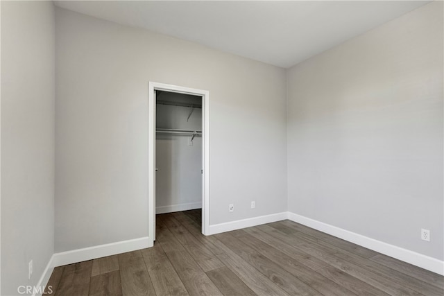 unfurnished bedroom featuring a closet, hardwood / wood-style flooring, and a walk in closet