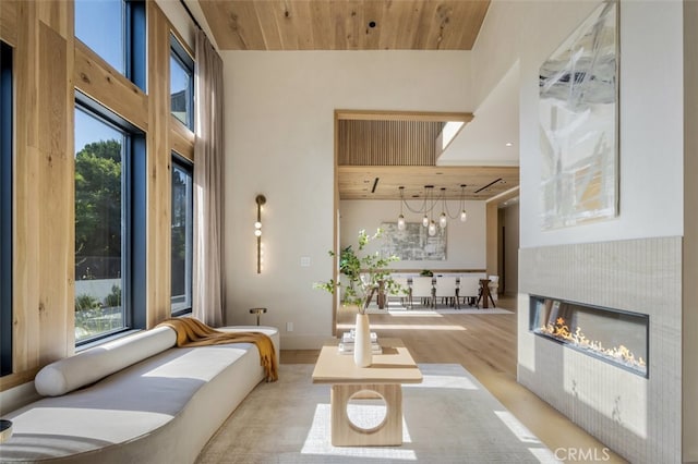 living room with a wealth of natural light, a chandelier, light wood-type flooring, and wooden ceiling