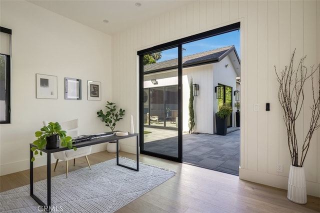 doorway to outside featuring light hardwood / wood-style flooring and wooden walls