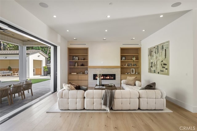 living room featuring built in features and light wood-type flooring