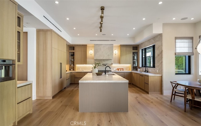 kitchen featuring a large island, sink, light hardwood / wood-style flooring, and stainless steel oven