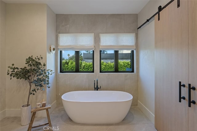 bathroom with a bathtub, a healthy amount of sunlight, and tile walls