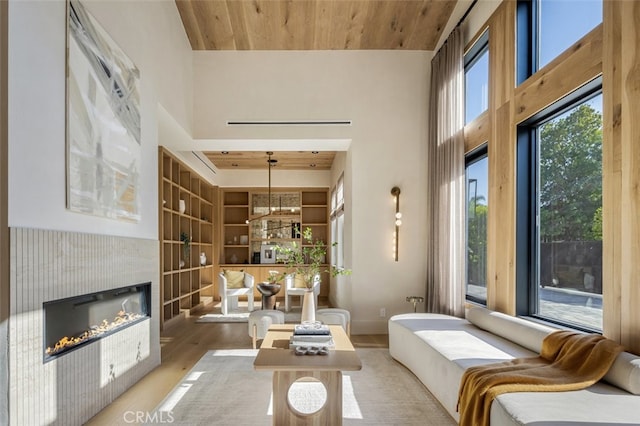 interior space with light hardwood / wood-style floors, wood ceiling, a high ceiling, and a fireplace