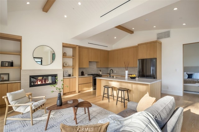 kitchen with refrigerator, beamed ceiling, sink, and light hardwood / wood-style floors