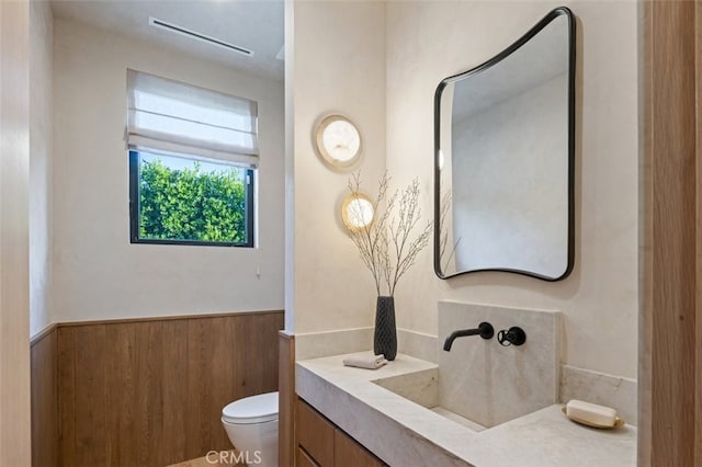 bathroom with vanity, toilet, and wooden walls