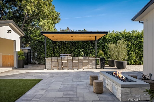 view of patio with an outdoor fire pit and a bar