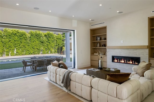 living room featuring light hardwood / wood-style flooring, a fireplace, and built in shelves