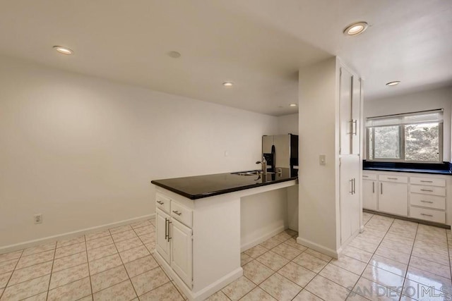 kitchen with white cabinets, stainless steel fridge with ice dispenser, and kitchen peninsula