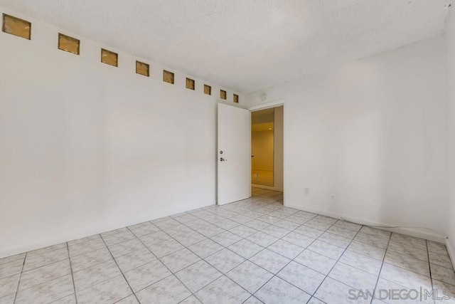 unfurnished room with a textured ceiling and light tile patterned flooring