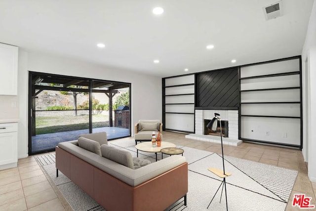 living room with a brick fireplace and light tile patterned flooring