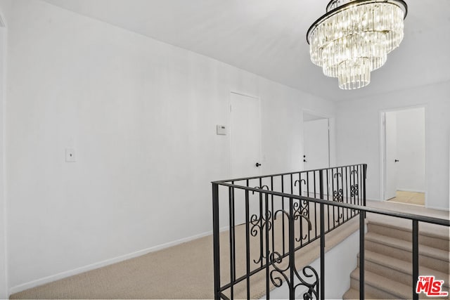 corridor featuring light carpet and an inviting chandelier