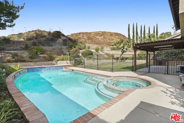 view of pool with a mountain view, an in ground hot tub, and a patio