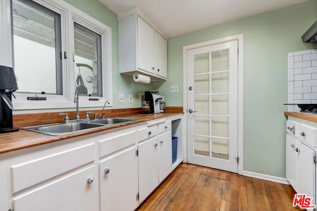 kitchen with light hardwood / wood-style floors, white cabinetry, and sink