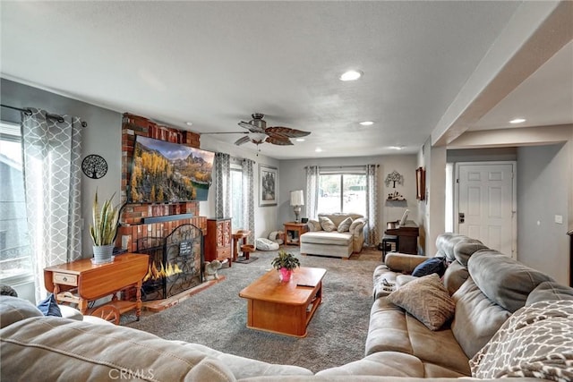 living room with a brick fireplace, carpet floors, and ceiling fan