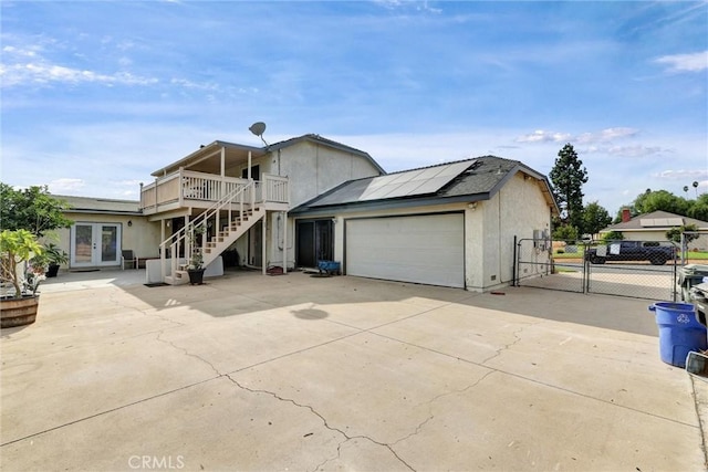 view of front of home featuring solar panels, a wooden deck, and french doors