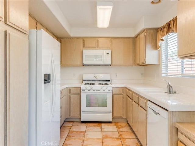 kitchen featuring white appliances, sink, and light brown cabinetry