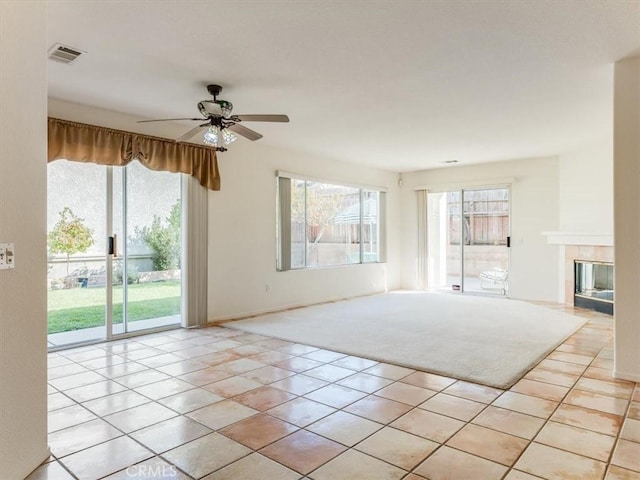 interior space featuring a fireplace, light tile patterned floors, and ceiling fan