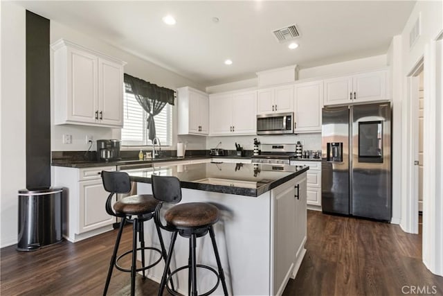 kitchen with a center island, white cabinetry, stainless steel appliances, and dark wood-type flooring