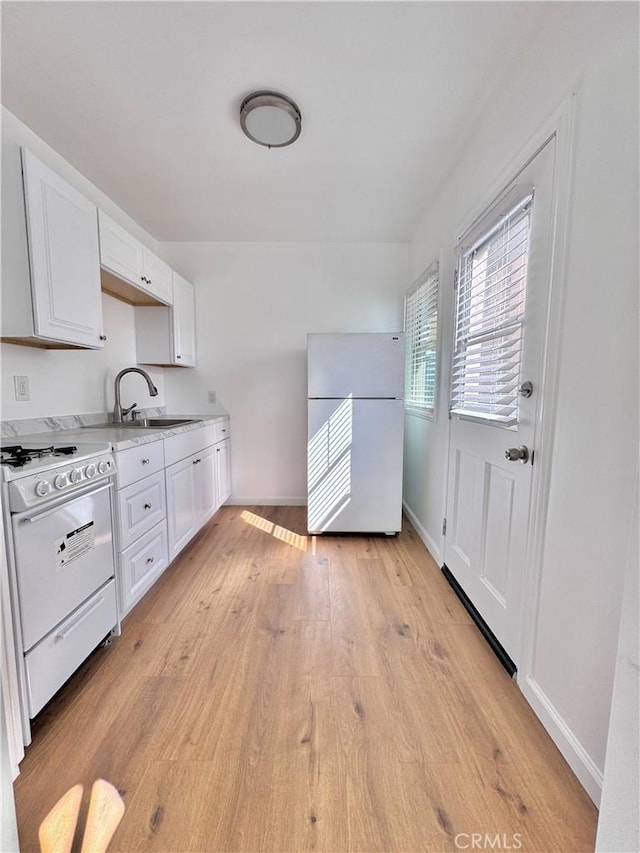 kitchen with sink, white cabinets, white appliances, and light hardwood / wood-style floors