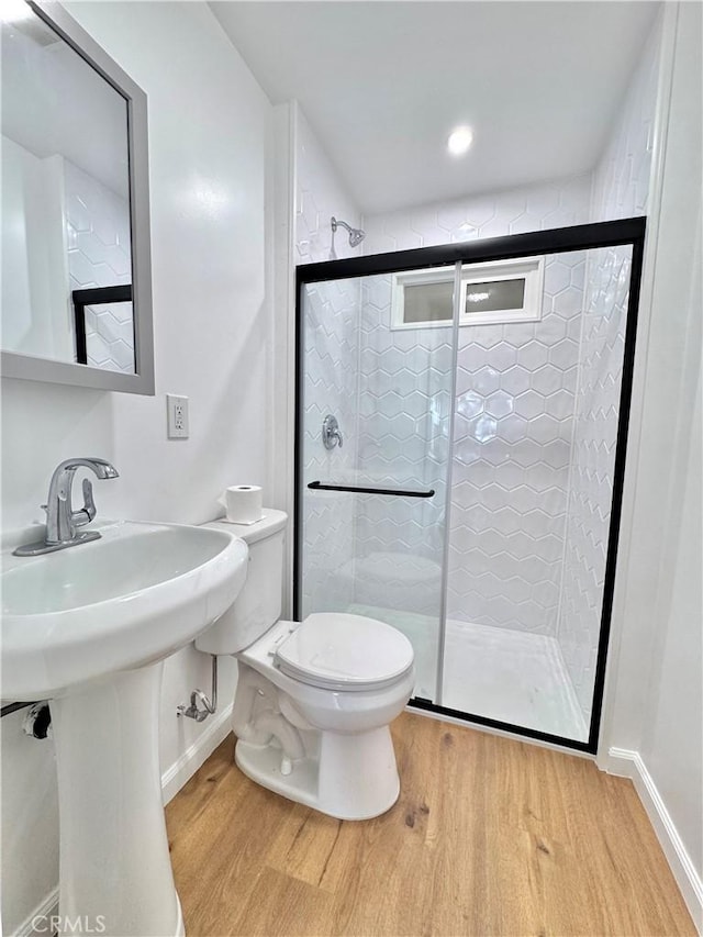 bathroom with toilet, a shower with door, and hardwood / wood-style floors