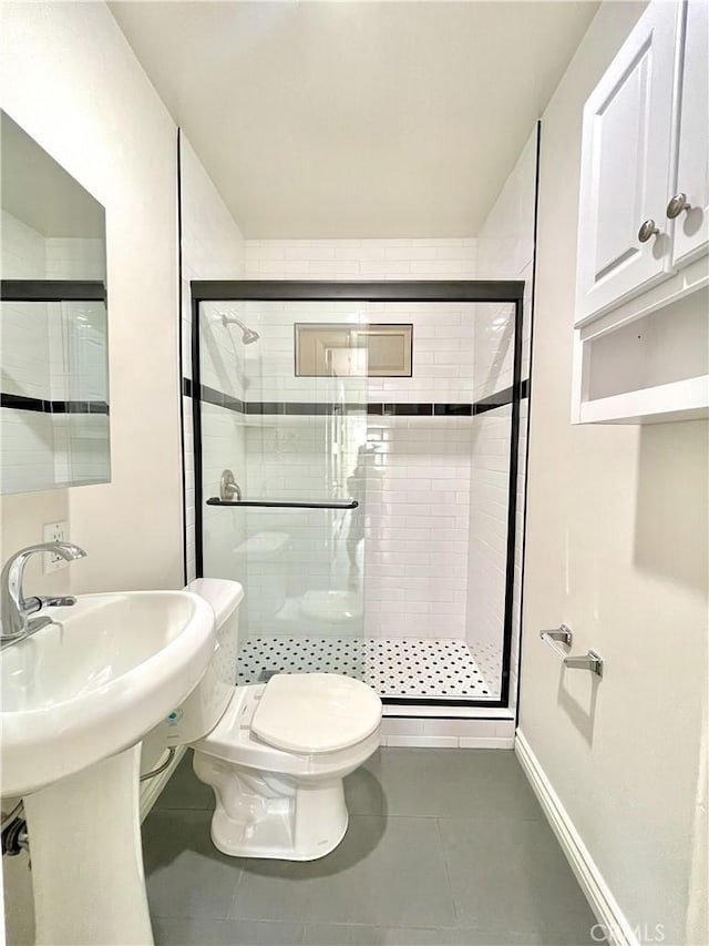 bathroom with toilet, a shower with shower door, and tile patterned flooring