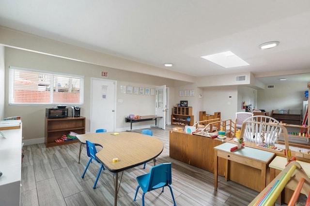 dining space featuring light hardwood / wood-style floors and a skylight