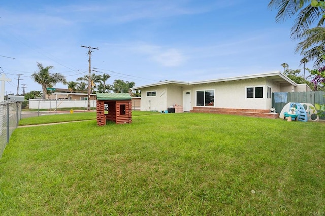 rear view of house with a shed and a yard