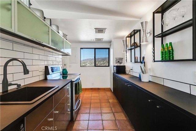 kitchen featuring a sink, visible vents, stainless steel range with electric cooktop, backsplash, and dark countertops