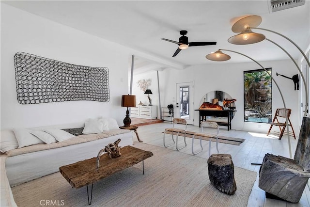 living area with a ceiling fan, visible vents, vaulted ceiling, and wood finished floors