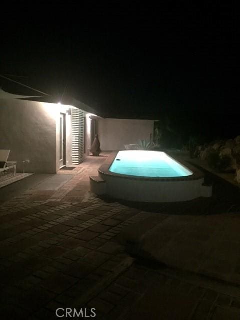 pool at twilight featuring a pool and a patio area