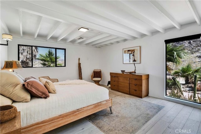bedroom with wood-type flooring and beam ceiling