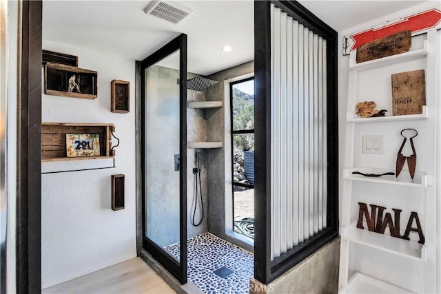 bathroom with visible vents, a walk in shower, and wood finished floors