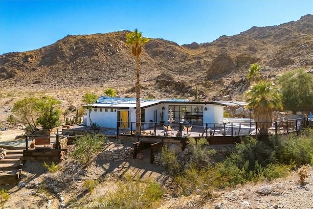 rear view of house with a deck with mountain view